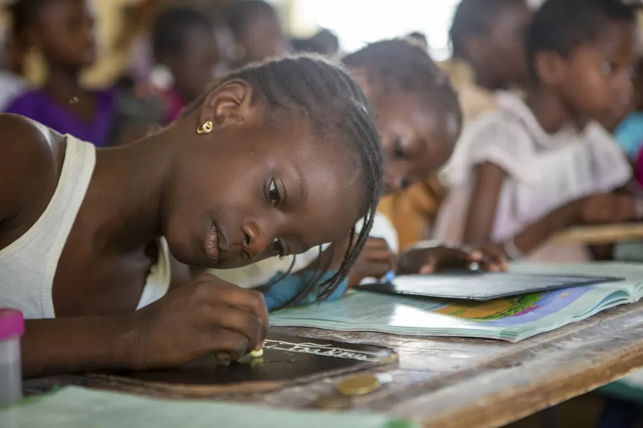 Young child sitting at a school desk and writing